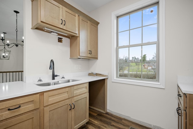 kitchen with sink, light brown cabinets, hanging light fixtures, an inviting chandelier, and dark hardwood / wood-style flooring