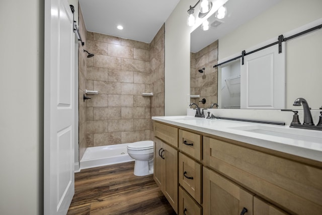 bathroom featuring tiled shower, toilet, vanity, and hardwood / wood-style flooring