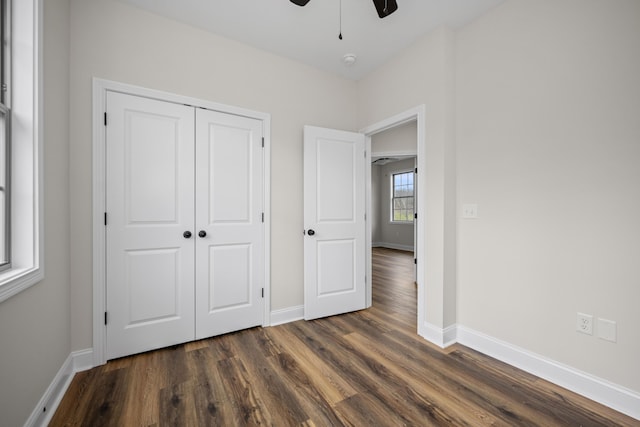 unfurnished bedroom with a closet, ceiling fan, and dark wood-type flooring