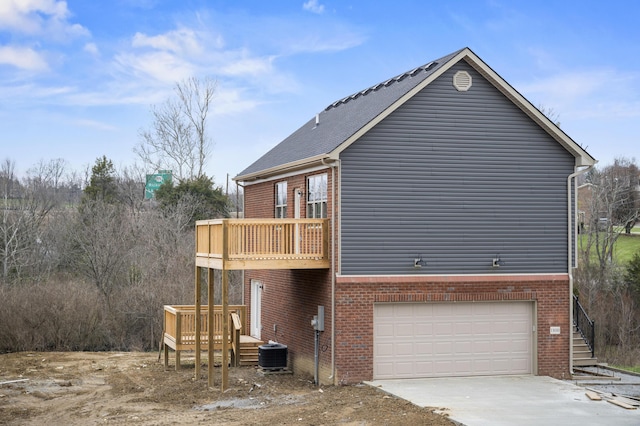 view of side of property featuring a balcony, a garage, and central AC unit