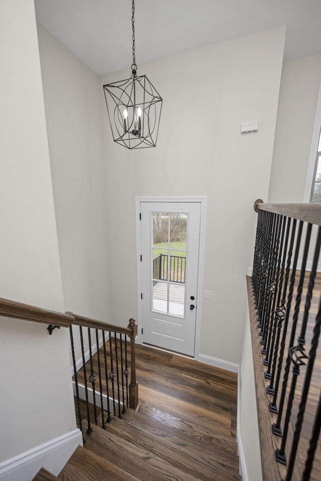 entryway featuring dark wood-type flooring and a chandelier