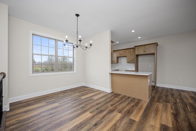 kitchen featuring a notable chandelier, dark hardwood / wood-style flooring, kitchen peninsula, and hanging light fixtures