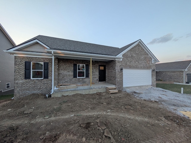 ranch-style house featuring a garage, brick siding, a porch, and driveway