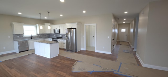 kitchen with backsplash, a kitchen island, appliances with stainless steel finishes, light wood-style floors, and white cabinets