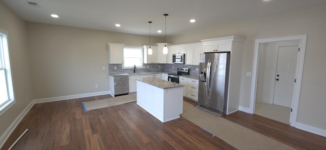 kitchen with a sink, tasteful backsplash, a center island, stainless steel appliances, and dark wood-style flooring