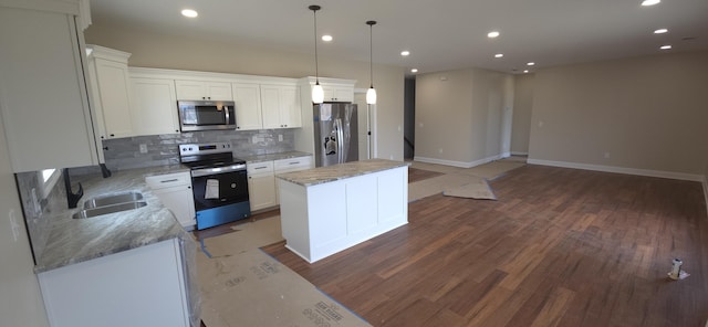 kitchen featuring a kitchen island, decorative backsplash, wood finished floors, stainless steel appliances, and a sink