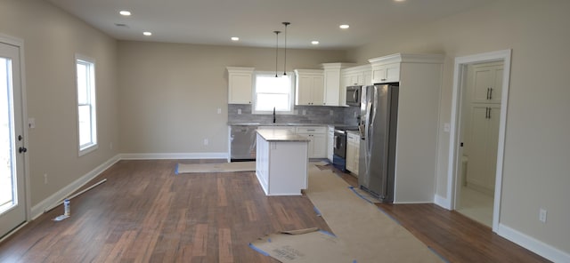 kitchen featuring a sink, dark wood-type flooring, a kitchen island, and appliances with stainless steel finishes