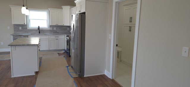 kitchen featuring backsplash, stainless steel appliances, wood finished floors, white cabinetry, and a sink