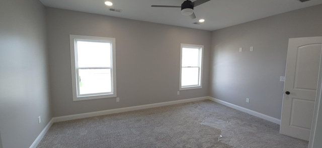 carpeted spare room featuring visible vents, a healthy amount of sunlight, baseboards, and ceiling fan