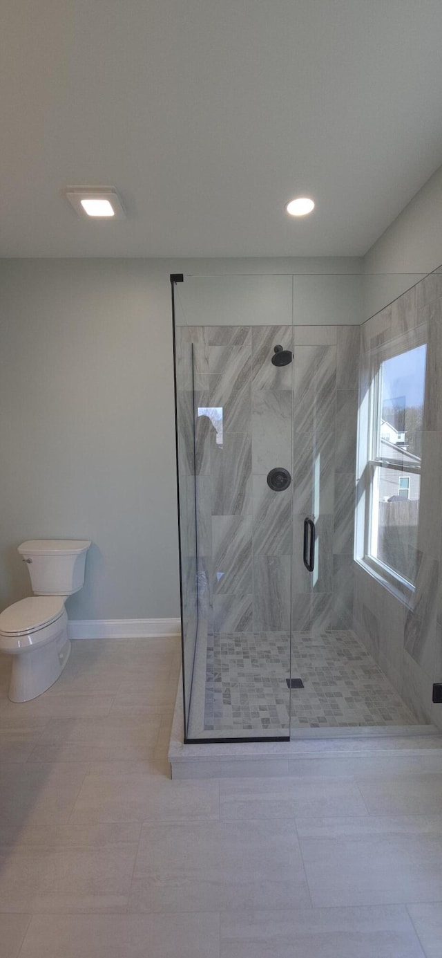 full bath featuring tile patterned flooring, toilet, baseboards, and a stall shower