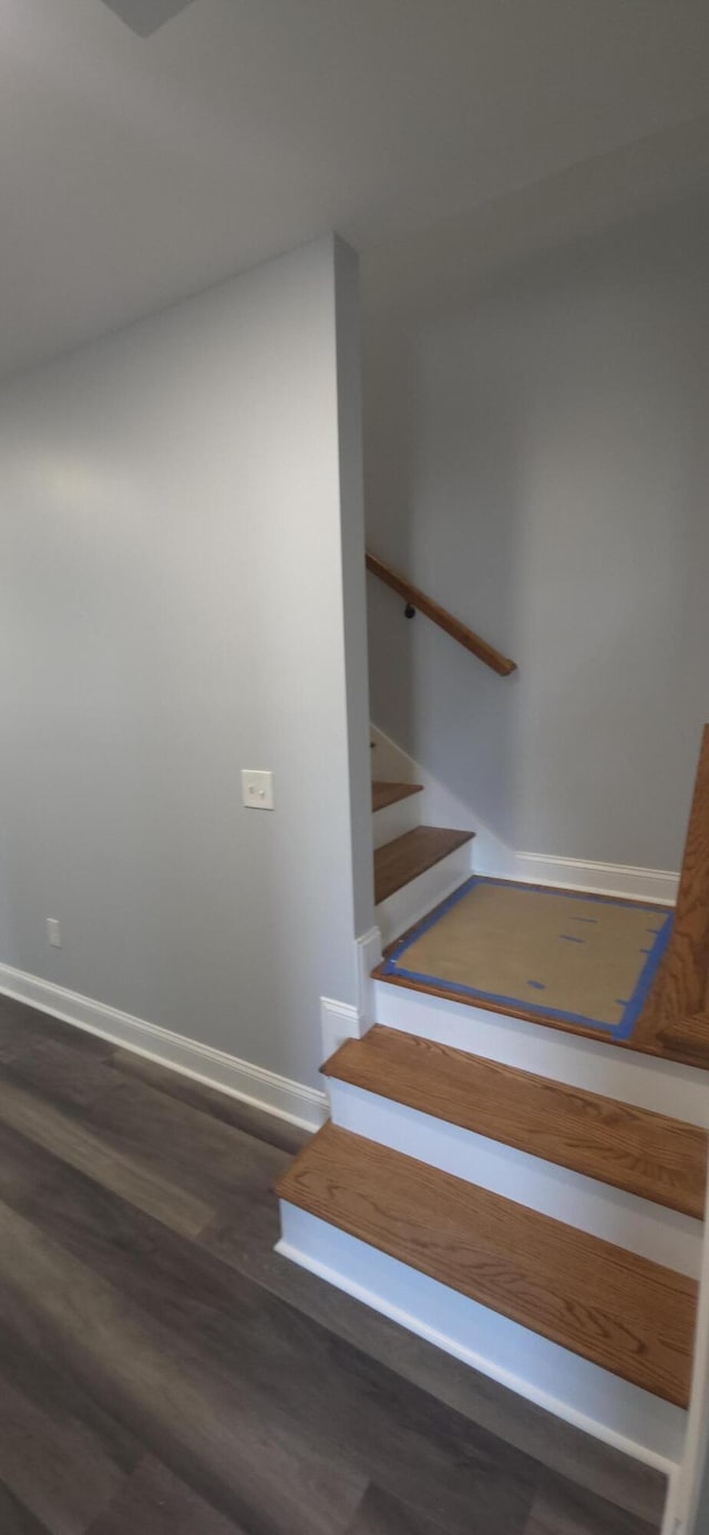 staircase featuring baseboards and wood finished floors