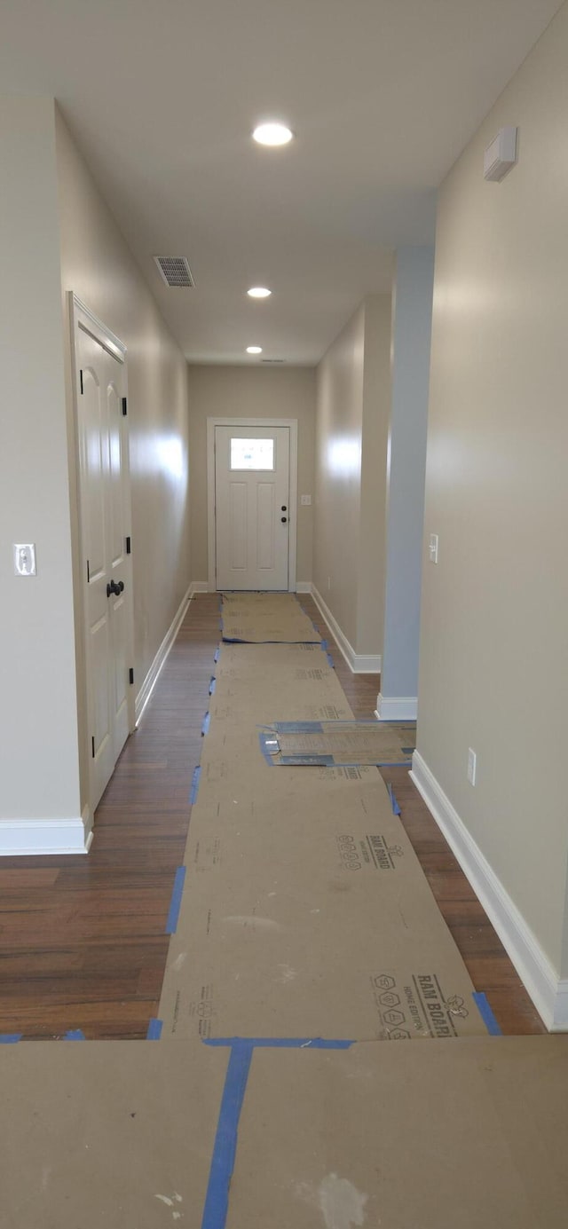 hall with wood finished floors, visible vents, and baseboards