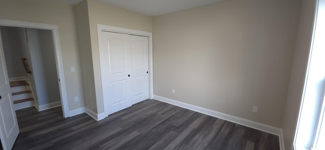 unfurnished bedroom featuring baseboards, dark wood-style flooring, and a closet