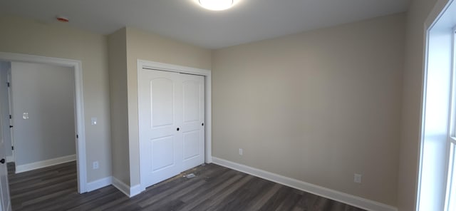 unfurnished bedroom featuring a closet, dark wood finished floors, and baseboards