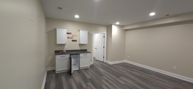 interior space with dark countertops, baseboards, beverage cooler, dark wood finished floors, and white cabinets