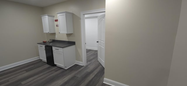 kitchen with dark countertops, dark wood finished floors, white cabinetry, and baseboards