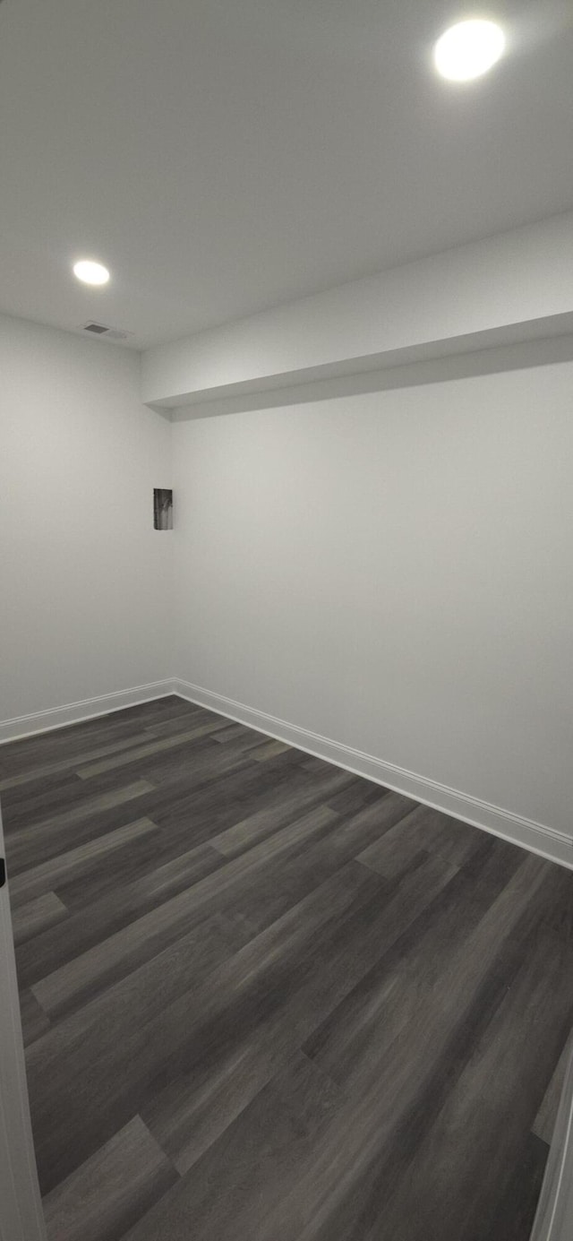 empty room featuring recessed lighting, baseboards, and dark wood-style flooring