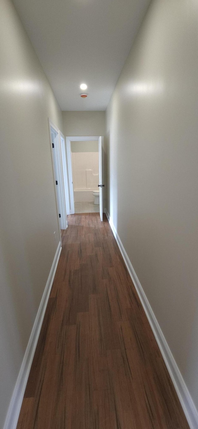 hallway with baseboards and dark wood-type flooring