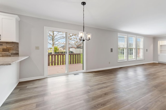 unfurnished dining area with baseboards, visible vents, ornamental molding, and wood finished floors