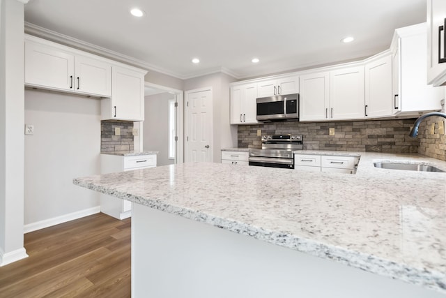 kitchen featuring appliances with stainless steel finishes, white cabinetry, a sink, and a peninsula