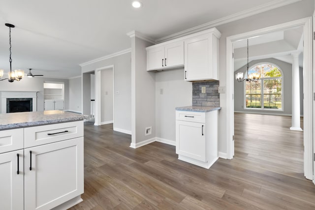 kitchen featuring a fireplace, white cabinets, open floor plan, backsplash, and crown molding