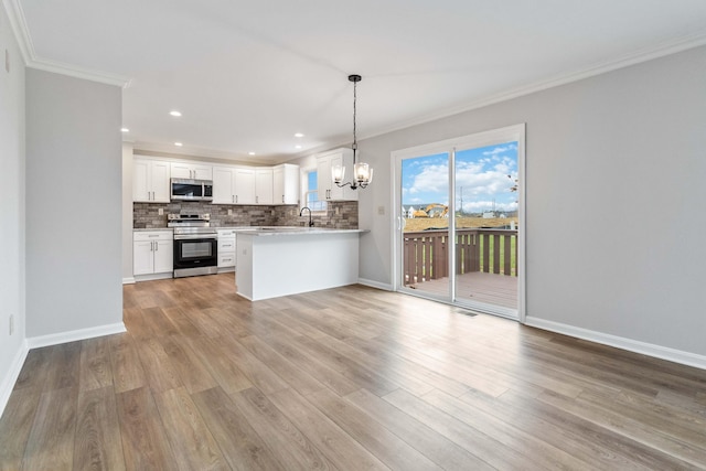 kitchen featuring a notable chandelier, a sink, open floor plan, appliances with stainless steel finishes, and tasteful backsplash