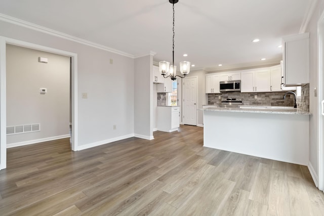 kitchen with visible vents, backsplash, appliances with stainless steel finishes, ornamental molding, and white cabinets