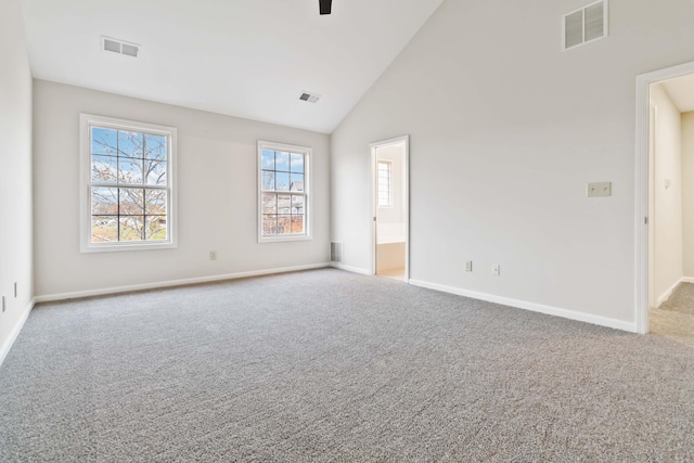 carpeted spare room featuring high vaulted ceiling, visible vents, and baseboards