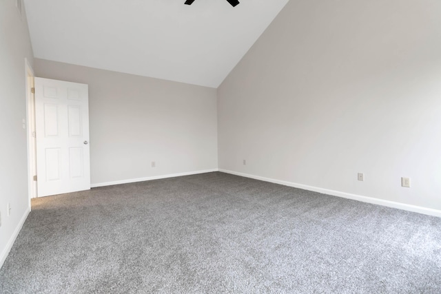 spare room featuring lofted ceiling, dark carpet, a ceiling fan, and baseboards