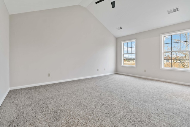 empty room with vaulted ceiling, carpet flooring, visible vents, and baseboards