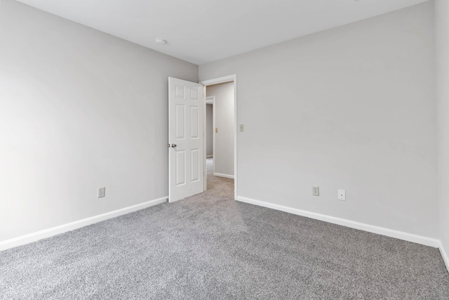 unfurnished room with carpet flooring and baseboards