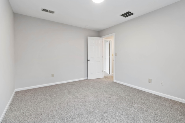 empty room with carpet, visible vents, and baseboards