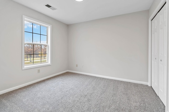 unfurnished bedroom featuring carpet floors, a closet, visible vents, and baseboards