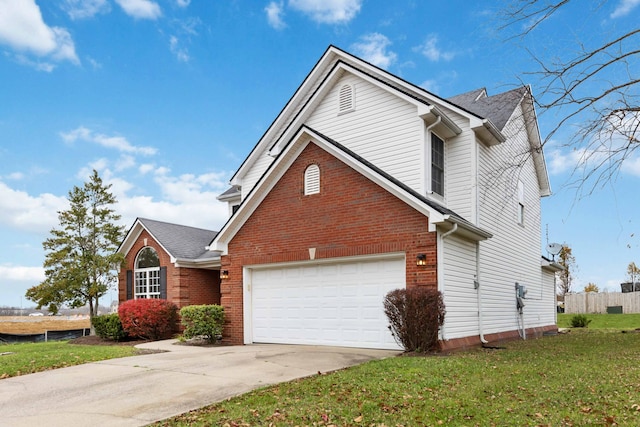 traditional-style home with concrete driveway, fence, brick siding, and a front yard