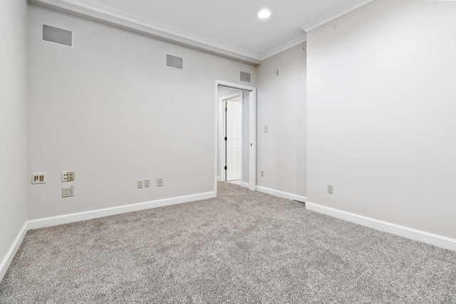 carpeted spare room featuring visible vents, baseboards, and crown molding