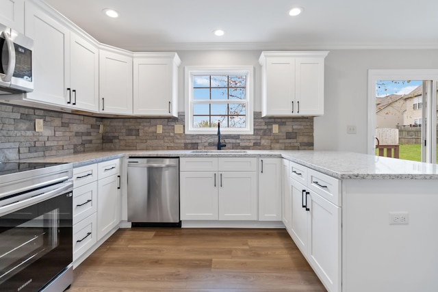 kitchen featuring a peninsula, crown molding, appliances with stainless steel finishes, and a sink