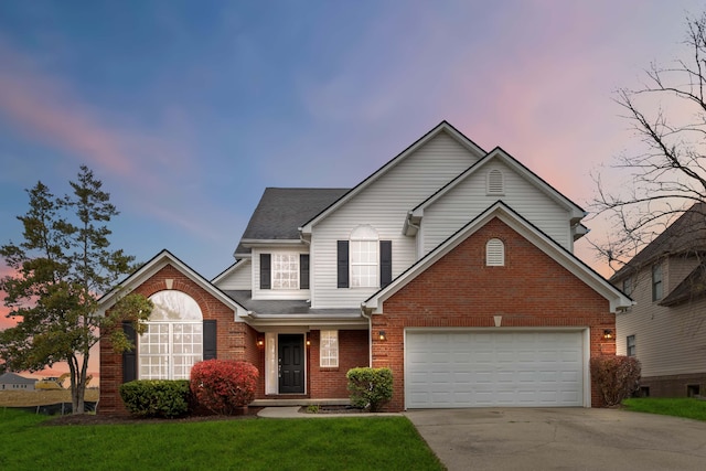 traditional-style house with a garage, brick siding, a shingled roof, concrete driveway, and a front yard