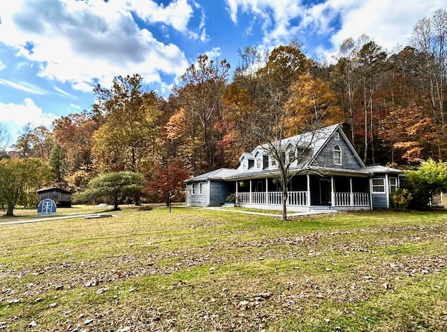 view of front of home with a porch, a storage unit, and a front lawn