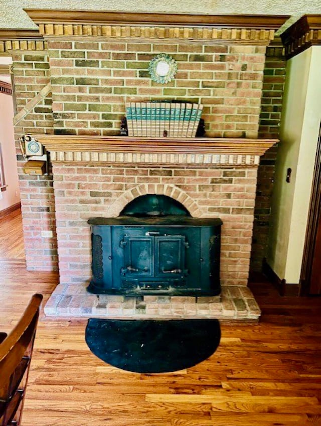 room details with a textured ceiling, hardwood / wood-style flooring, and a wood stove