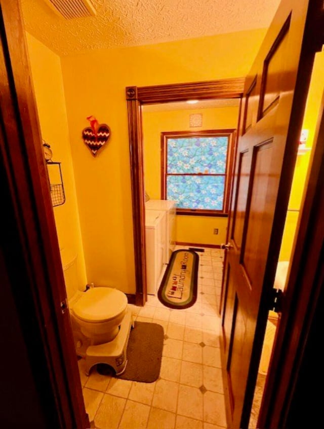 bathroom featuring a textured ceiling, washing machine and dryer, and tile patterned floors