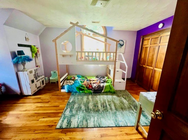 bedroom featuring a textured ceiling, lofted ceiling, and hardwood / wood-style flooring