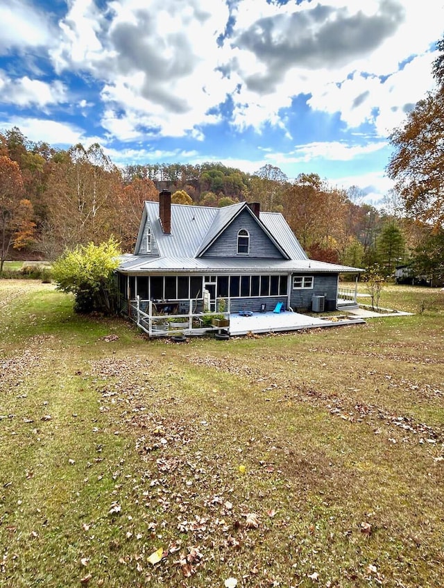 rear view of house featuring a sunroom, a patio area, a yard, and central AC