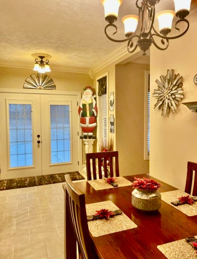 dining space with an inviting chandelier, ornamental molding, a textured ceiling, and french doors