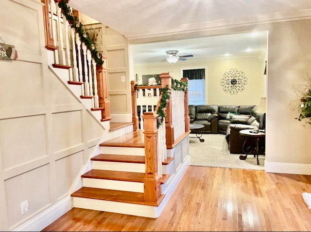 stairs featuring hardwood / wood-style flooring, ceiling fan, and crown molding