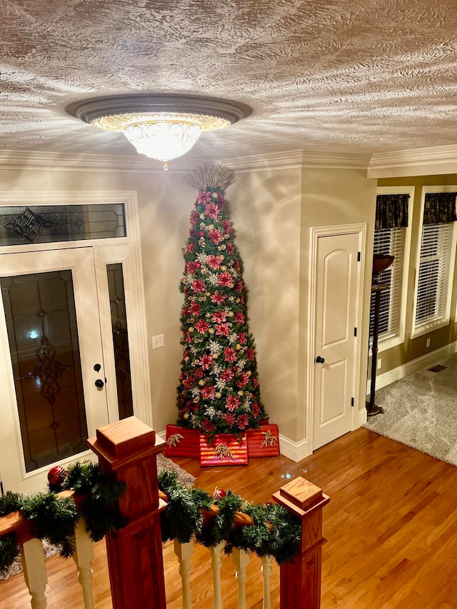 interior space featuring a textured ceiling, hardwood / wood-style flooring, and crown molding