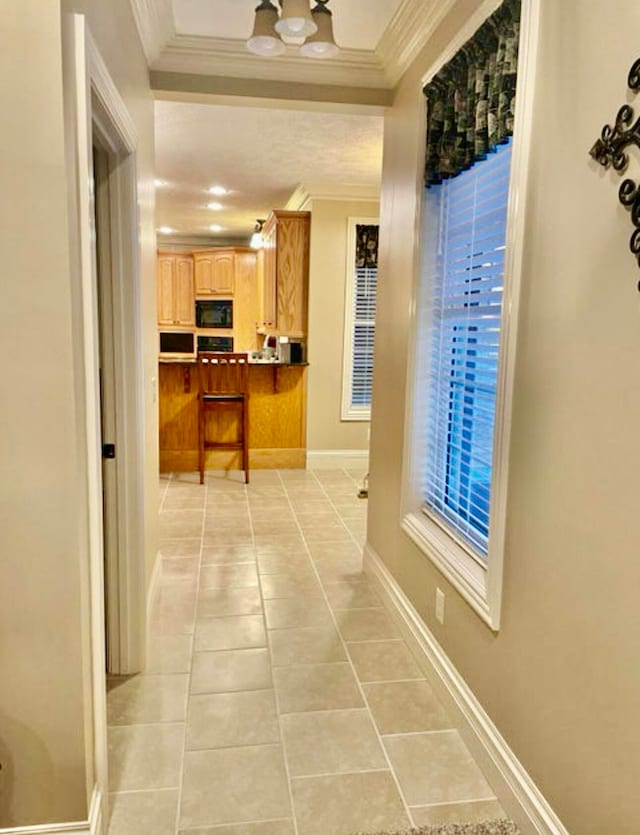 hall featuring light tile patterned floors and crown molding