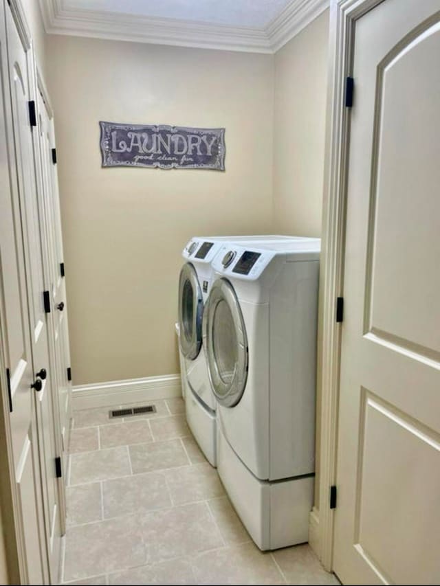 washroom featuring washer and clothes dryer, ornamental molding, and light tile patterned flooring