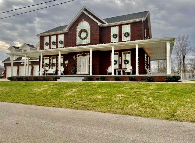 view of front of house with a garage, covered porch, and a front lawn