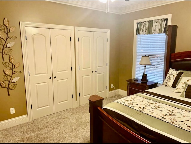 carpeted bedroom featuring multiple closets and crown molding