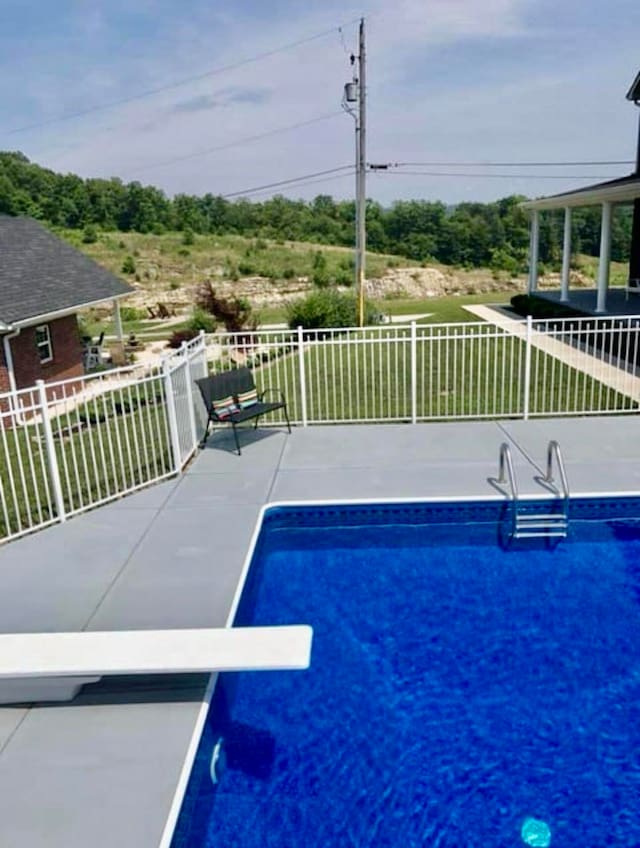 view of swimming pool with a diving board